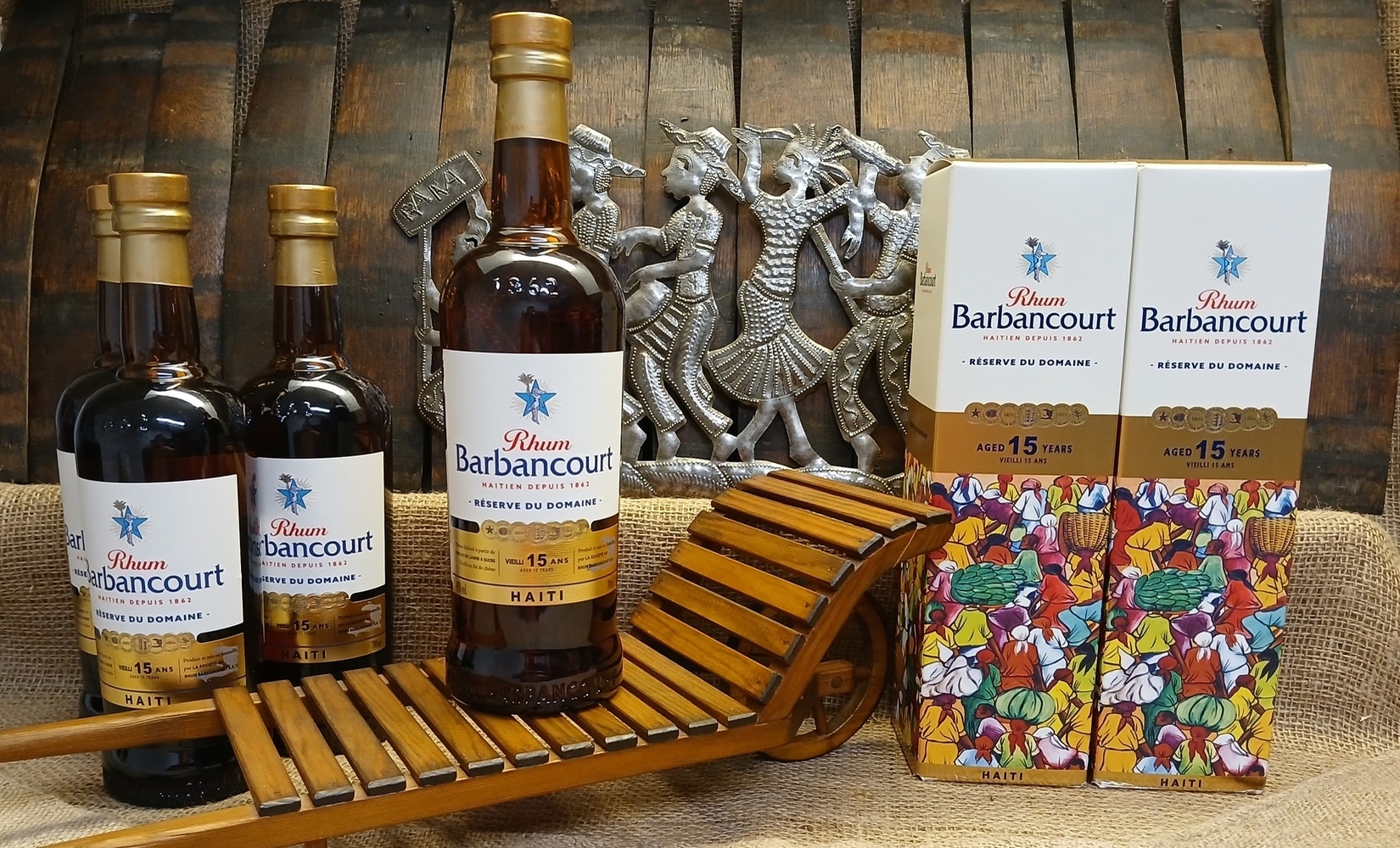 Abbildung 8 - Vorderseite der Abfüllung - Rhum Barbancourt® - 15 Jahre gelagert - Réserve du Domaine - Delphine Gardère - 2022 mit Geschenkebox, Blechornament Rara-Festumzug, hölzerner Fasskarre.